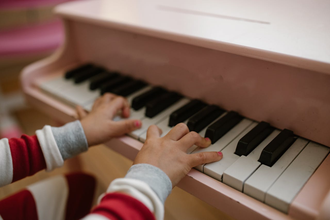 Close-up of childs hands playing a pink toy piano indoors.