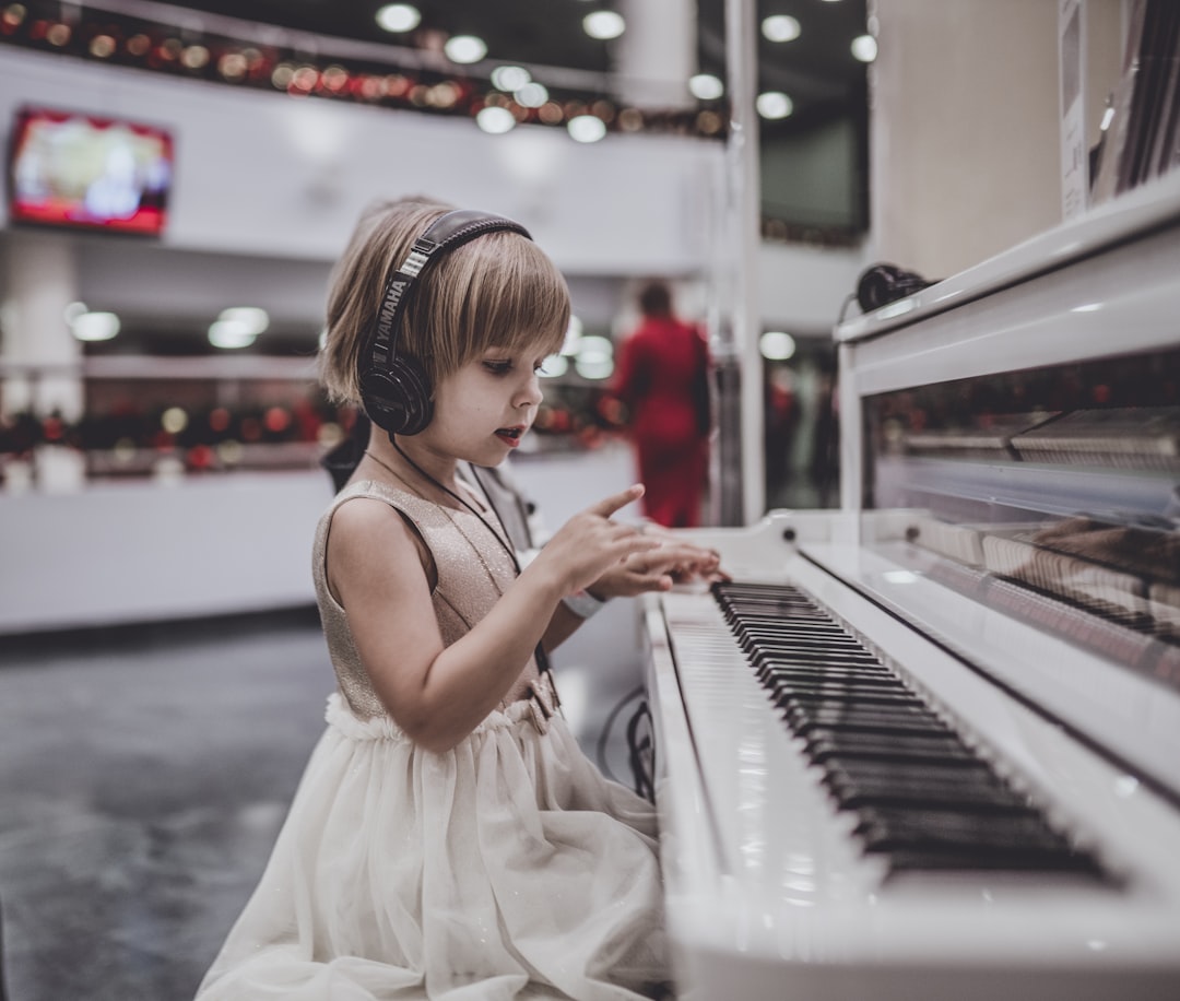 girl-wearing-headphones-sitting-in-front-of-white-piano-uazyrd0qdbg
